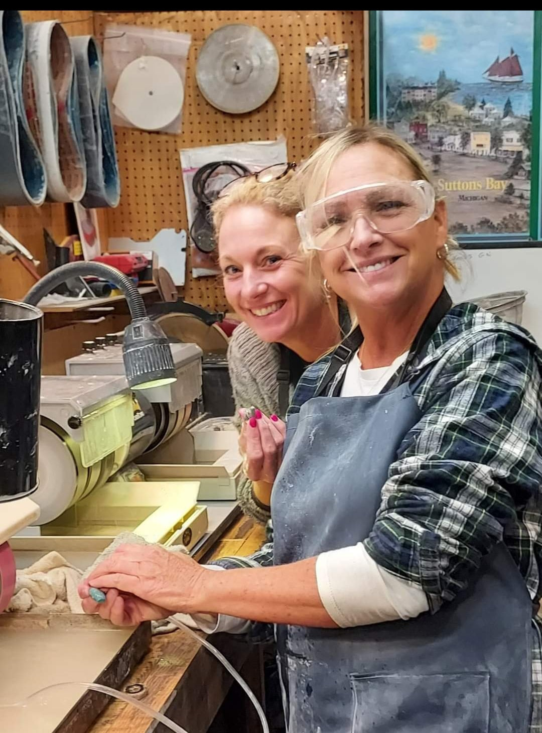 Two participants polishing stones at the Northport Trading Post workshop bench
