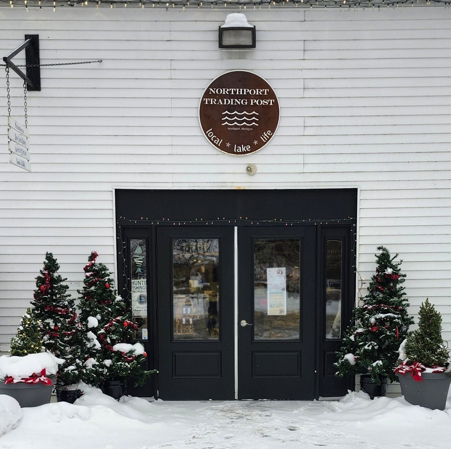 Northport Trading Post's round sign and black double-door storefront